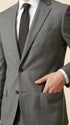 Man wearing the F.Ferrante FEU230 tailored two-button suit in grey, styled with a white shirt, charcoal tie and dark brown Oxford shoes